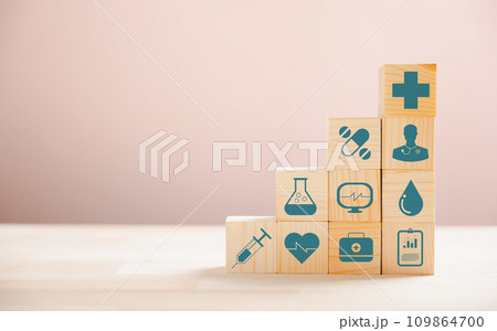 Pyramid crafted from wooden cubes symbolizes healthcare and insurance principles. Medical insurance icon atop indicates security. Blue background provides copyspace for Health Insurance concept. Pyramid crafted from wooden cubes symbolizes healthcare and insurance principles. Medical insurance icon atop indicates security. Blue background provides copyspace for Health Insurance concept. 109864700