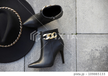Stylish black leather boots and hat outdoors in the street 109865133