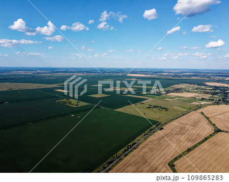 Beautiful agricultural landscape, open field with blue sky and white clouds. Farmfields from a bird's eye view. Beautiful agricultural landscape, open field with blue sky and white clouds. Farmfields from a bird's eye view. 109865283