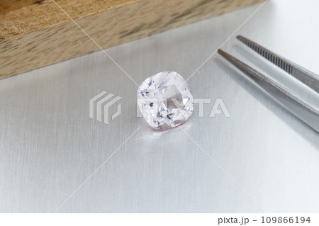 macro mineral faceted stone Morganite with tweezers on a gray background 109866194