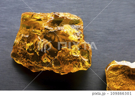 Large amber stone illuminated by sunlight on a black background close-up 109866301