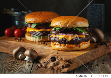 Two delicious homemade burgers of beef, cheese and mushrooms on an wooden table. Fat unhealthy food 109866439