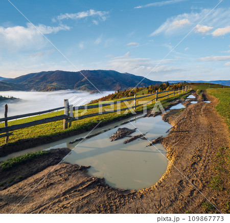 Hazy and overcast autumn Carpathian Mountains and dirty countryside path, Ukraine. Hazy and overcast autumn Carpathian Mountains and dirty countryside path, Ukraine. 109867773