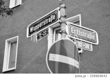 Greyscale shot of street signs indicating the intersection of Wupperstrasse and Erftstrasse streets 109869642