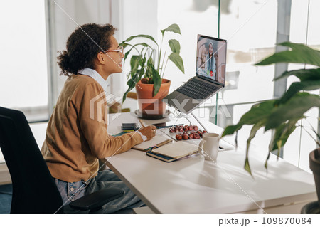 Female freelancer have video conference with client and making notes sitting in cozy coworking 109870084