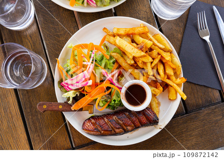 Juicy roasted duck magret served sauce framboise, french fries and vegetables 109872142