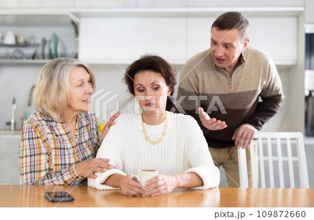 Family members quarreling in the kitchen and old woman trying to calm angry woman 109872660