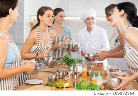 Young female visitor has nice conversation with person facing buddy vis-a-vis at culinary courses Young female visitor has nice conversation with person facing buddy vis-a-vis at culinary courses 109872964