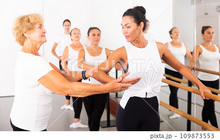 Various aged women exercising ballet moves with trainer Various aged women exercising ballet moves with trainer 109873553