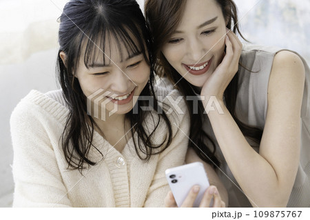 スマホを使う仲良しの姉妹 109875767
