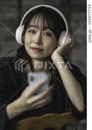シックな部屋でスマホ音楽を聴く女性 シックな部屋でスマホ音楽を聴く女性 109877754
