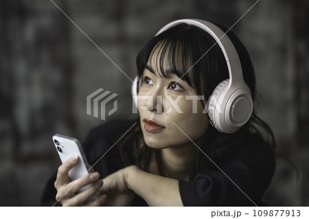 シックな部屋でスマホ音楽を聴く女性 109877913