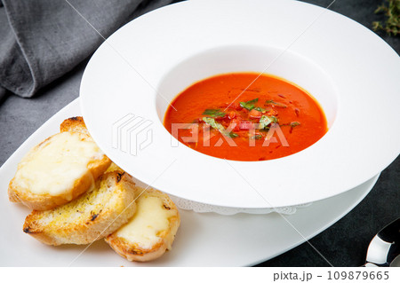 borscht with herbs in a white plate with pieces of bread, side view 109879665