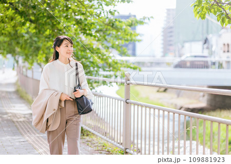 オフィス街の川沿いを歩く30代〜40代のビジネスウーマン オフィス街の川沿いを歩く30代〜40代のビジネスウーマン 109881923