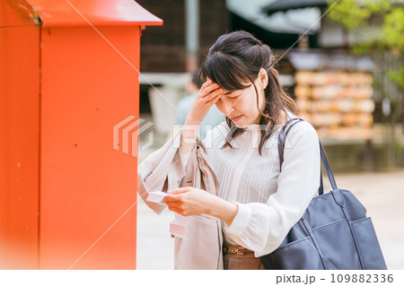 神社でおみくじを引くアジア人女性 109882336