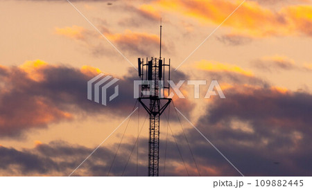 Telecommunications tower with beautiful sky at sunrise. Electronic antenna with clouds and orange sky background. Modern business communication Telecommunications tower with beautiful sky at sunrise. Electronic antenna with clouds and orange sky background. Modern business communication 109882445