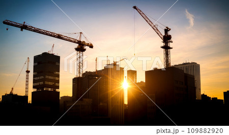 New construction site with crane and mechanical equipments on sunset background. Construction site crane. Silhouette building site. New construction site with crane and mechanical equipments on sunset background. Construction site crane. Silhouette building site. 109882920