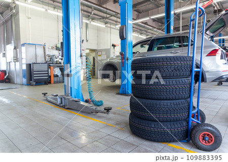 A set of tires for seasonal replacement near the lift in the tire workshop. A set of tires for seasonal replacement near the lift in the tire workshop. 109883395