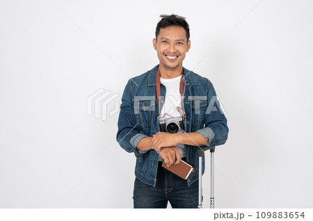 A positive Asian man with his passport and luggage is standing on an isolated white background. 109883654