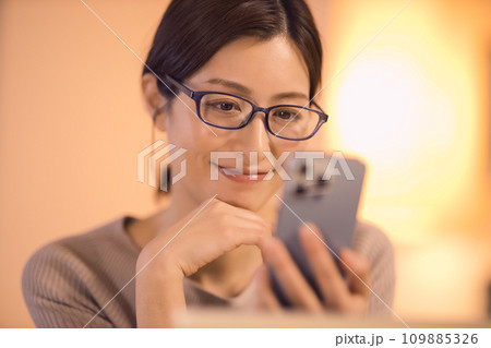 リビングでスマホを見る女性　ナイトルーティーン 109885326