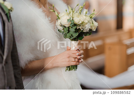 A beautiful wedding bouquet in the hands of the bride. Bouquet with white flowers in the hands of the bride 109886582