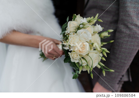 A beautiful wedding bouquet in the hands of the bride. Bouquet with white flowers in the hands of the bride 109886584