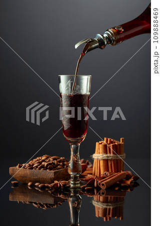 Coffee liquor is poured from a bottle into a glass. 109888469