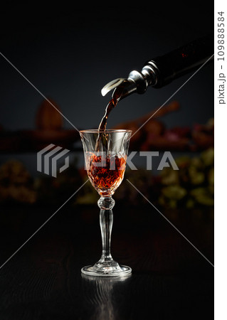 Brown herbal liquor or rum is poured from a vintage bottle. Brown herbal liquor or rum is poured from a vintage bottle. 109888584
