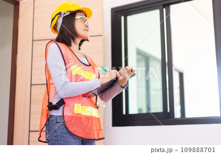 Professional women home Inspector surveyor wearing vests and hard hat at new property Professional women home Inspector surveyor wearing vests and hard hat at new property 109888701