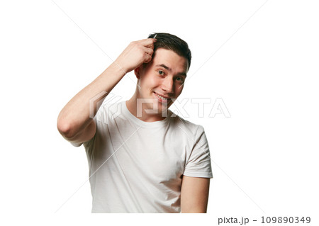 Portrait of attractive young man looks at camera and smile while combing his hair against white background. Concept of hair care and barber. 109890349