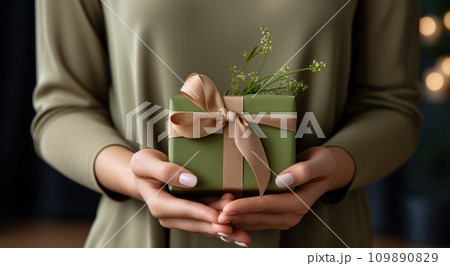 hands up to a gift which is wrapped in green 109890829