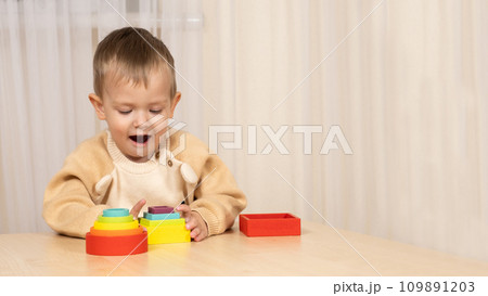 A two-year-old boy plays with wooden toys to develop logic and motor skills A two-year-old boy plays with wooden toys to develop logic and motor skills 109891203