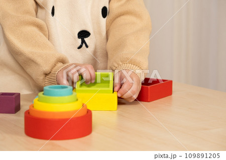 Little boy playing with wooden multicolored Montessori toys. Hands close-up Little boy playing with wooden multicolored Montessori toys. Hands close-up 109891205