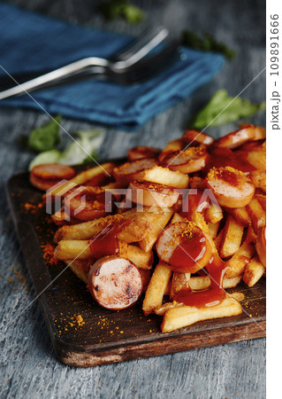 german currywurst and chips on a chopping board 109891666