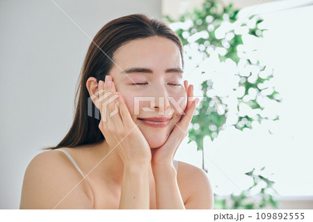 顔をマッサージしてスキンケアをする30代女性 109892555