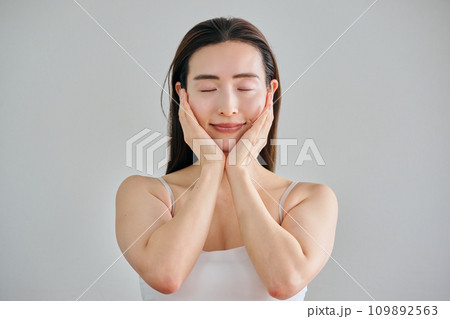 顔をマッサージしてスキンケアをする30代女性 顔をマッサージしてスキンケアをする30代女性 109892563
