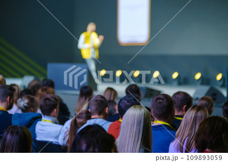 Back view of businesspeople listening to male speaker on stage during global presentation at conference hall  109893059
