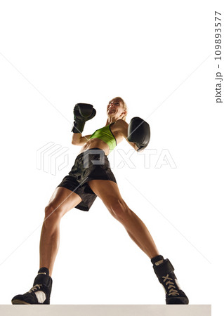 Bottom view of muscular young woman, boxing athlete in motion, training, punching isolated over white background. Sport, healthy and active lifestyle Bottom view of muscular young woman, boxing athlete in motion, training, punching isolated over white background. Sport, healthy and active lifestyle 109893577