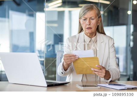 Businesswoman boss received letter mail notification message with bad news, upset and sad senior woman reading news data , female worker inside office at workplace. Businesswoman boss received letter mail notification message with bad news, upset and sad senior woman reading news data , female worker inside office at workplace. 109895330