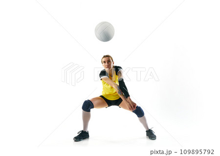 Concentrated young woman in uniform training, playing volleyball, hitting ball isolated over white background. Sport, active and healthy lifestyle 109895792