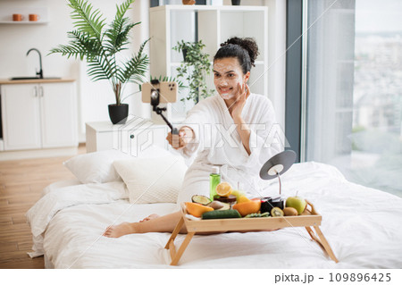 Blogger using camera of smartphone for media content applying facial mask Blogger using camera of smartphone for media content applying facial mask 109896425