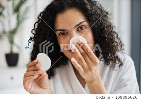 Multiracial woman removing cosmetics from nose area Multiracial woman removing cosmetics from nose area 109896626