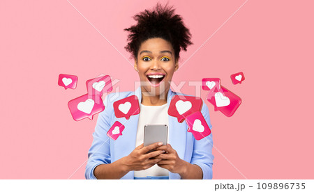Glad surprised young african american woman with open mouth has romantic chat with hearts on phone 109896735