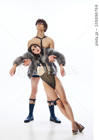 Full length portrait of young freaky shirtless couple, dressed in provocative costumes posing against white studio background. 109896769