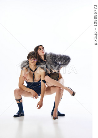 Full length portrait of young freaky couple dressed in provocative costumes posing against white studio background. 109896773