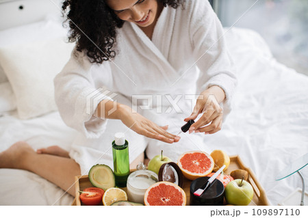 Top view of hands of lady in dressing gown, paints nails Top view of hands of lady in dressing gown, paints nails 109897110