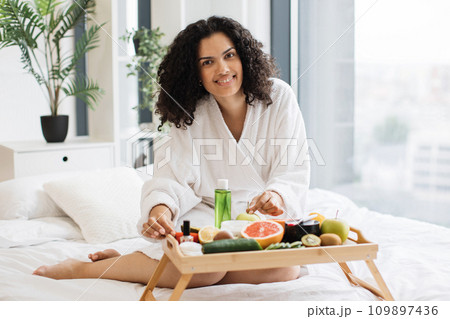 African lady touching to fruits and cosmetic containers on tray table African lady touching to fruits and cosmetic containers on tray table 109897436