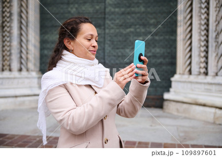 Happy woman photographing the medieval Italian city of Como, standing against the door of Santa Maria Maggiore cathedral Happy woman photographing the medieval Italian city of Como, standing against the door of Santa Maria Maggiore cathedral 109897601