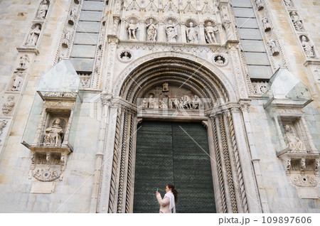 Woman standing at the door of Santa Maria Maggiore Cathedral and the building's exterior structures carved in stone Woman standing at the door of Santa Maria Maggiore Cathedral and the building's exterior structures carved in stone 109897606
