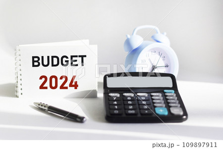 BUDGET 2024 written on a notepad and white background and with a calculator clock BUDGET 2024 written on a notepad and white background and with a calculator clock 109897911